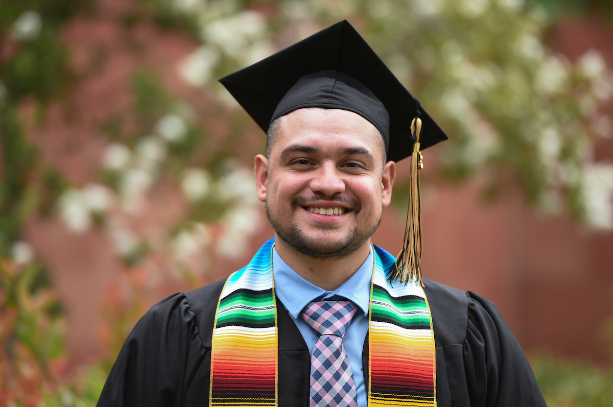 Male graduate wearing black cap and gown.