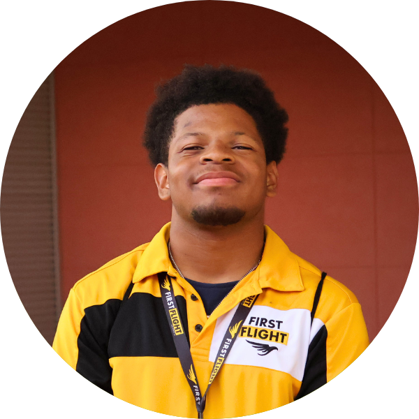 A man smiling with a yellow polo and black head / facial hair.