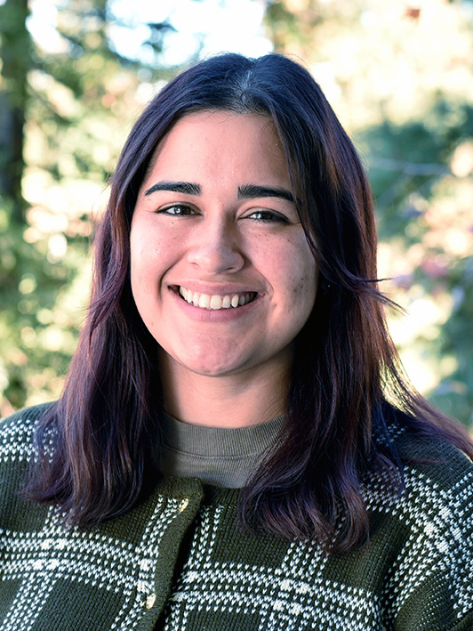 A person with shoulder-length hair and a bright smile.