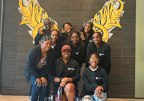 A group of students smiling with wings in the background.