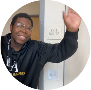 Man with a black sweater and glasses waving his hand.