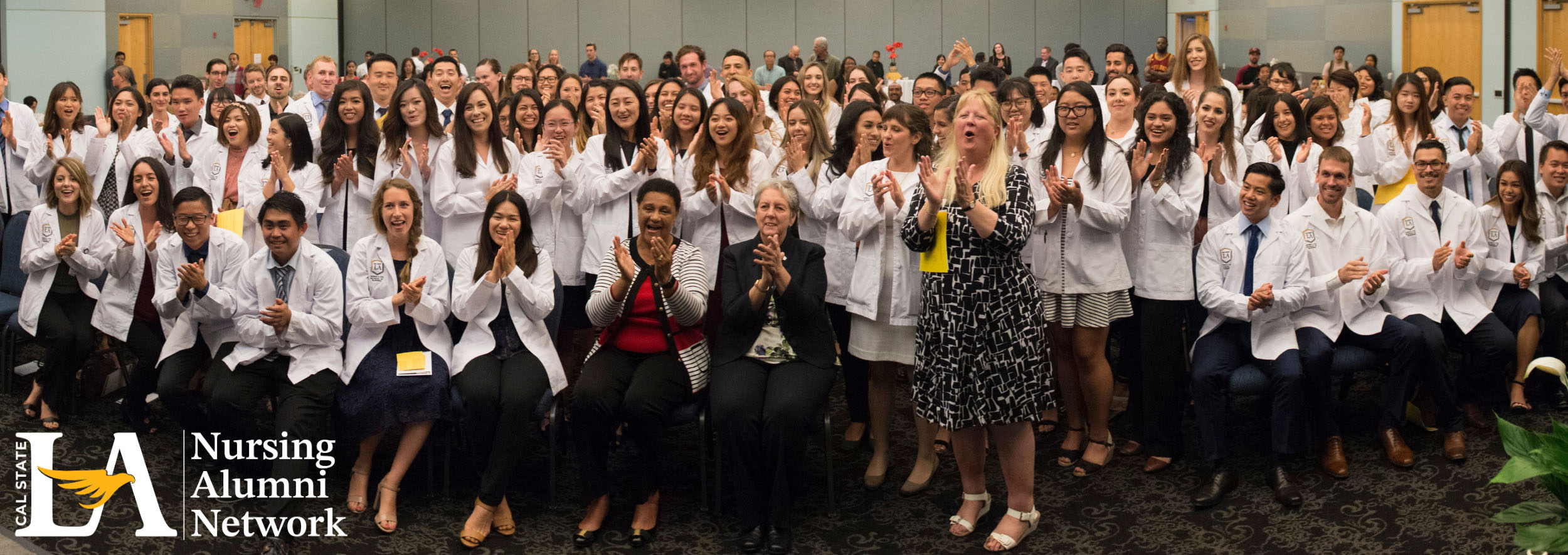 Group of nurses in white coats cheering and smiling