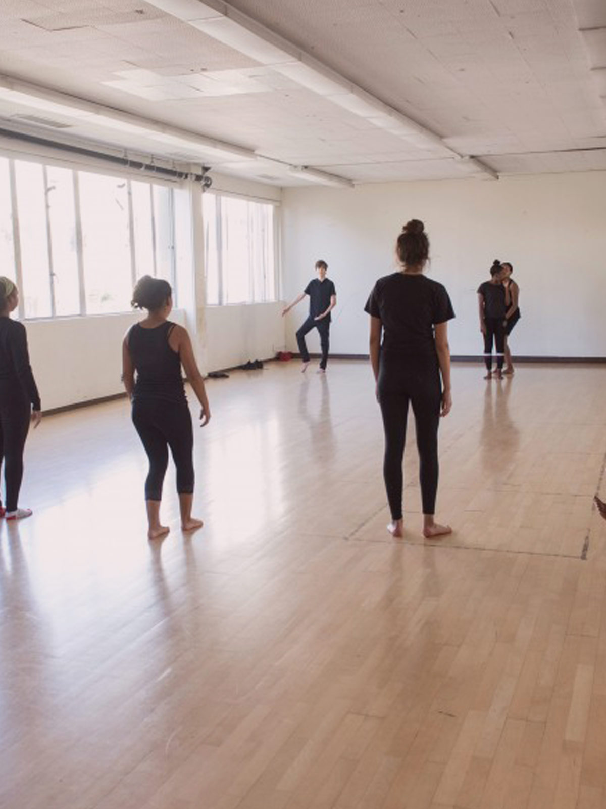 A dance studio with many dancers practicing in it.