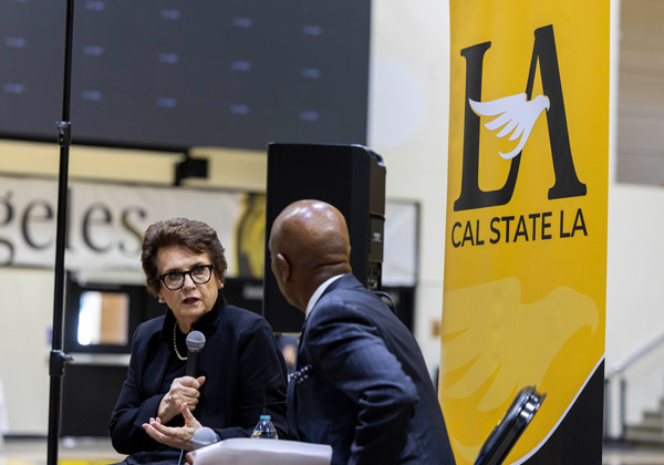 Two people having a conversation in front of a yellow banner.