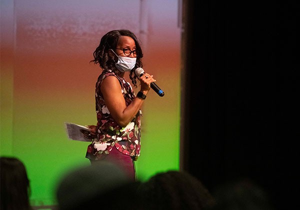 Faculty with a microphone speaking from a stage.