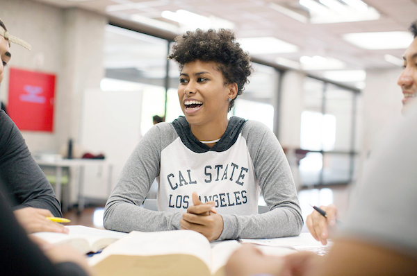 student sitting at a table smiling at another student