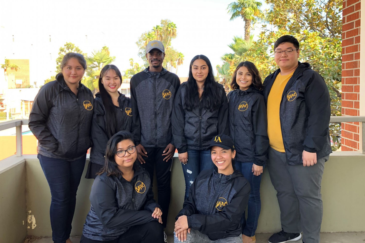 Group  of people wearing matching SHAC zip-up windbreaker jackets.