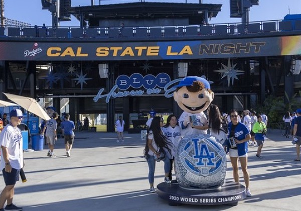 Group of alumni posing for photo with Bobblehead character at Dodger Stadium. 