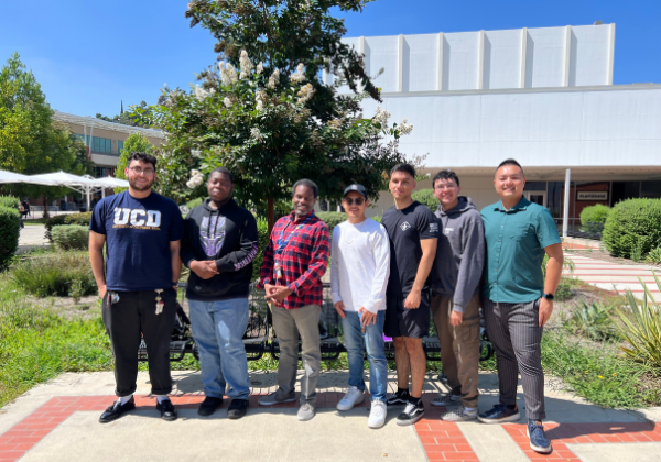 A group of men smiling in front of a white building.