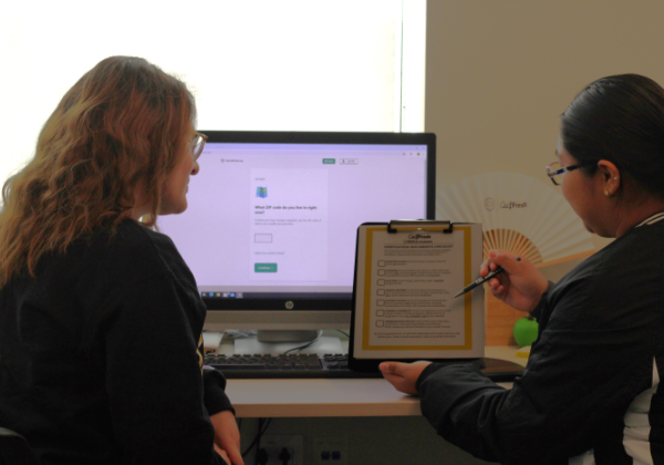 two students sitting next to each other, one is holding a clipboard