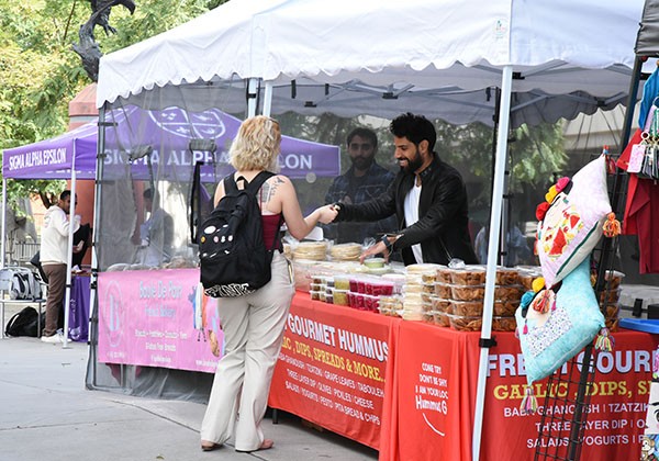 A student making a purchasing at a booth selling hummus.