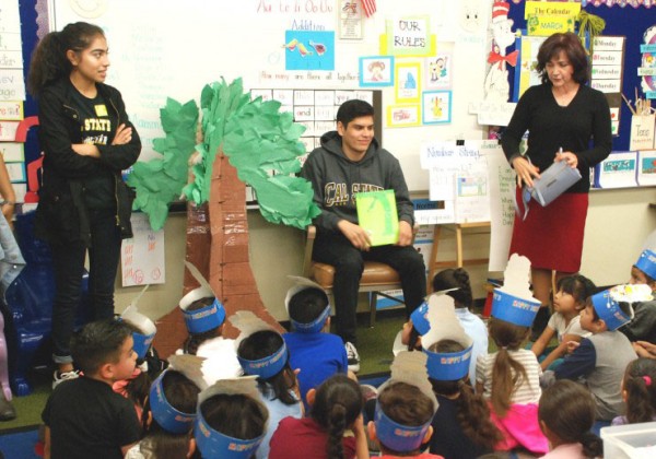 A student reading to a group of young children.