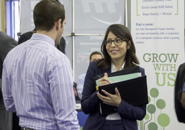 Student in professional clothes talks to an employer at the career fair