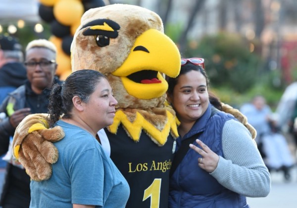 Two people posing with Eddie the Eagle