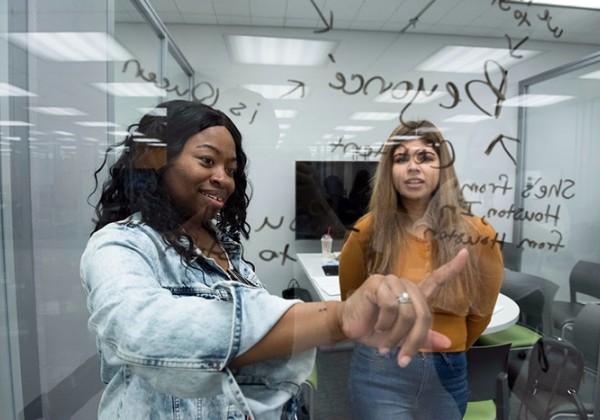 Two women looking at writing on glass