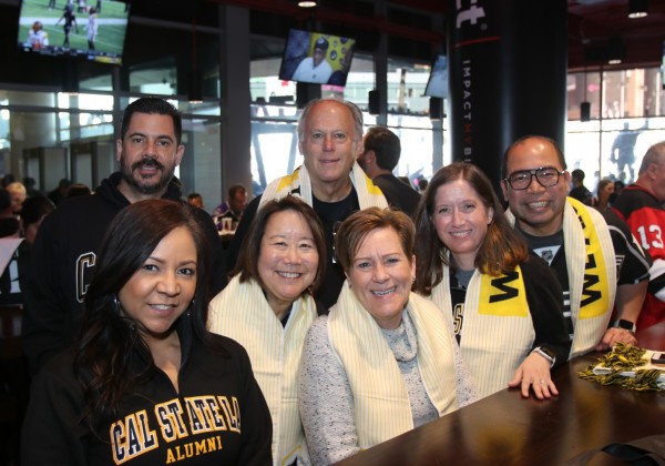 Group shot of seven alumni smiling