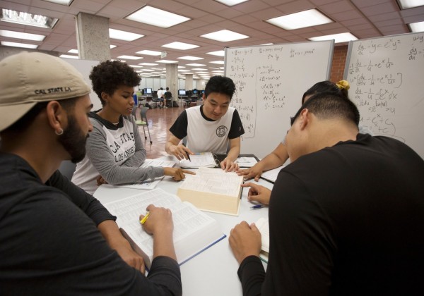 students gather around in library and share notes 