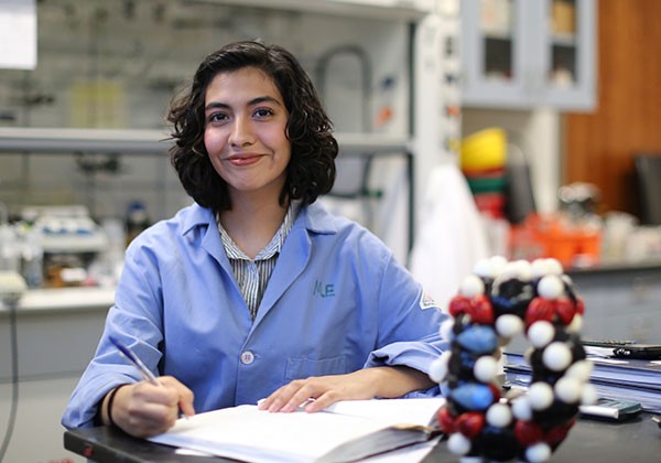 Latina student in blue labcoat in a lab