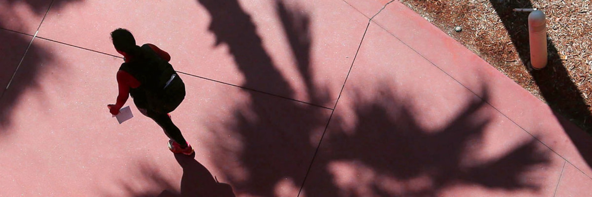 A student walking on red pavement.