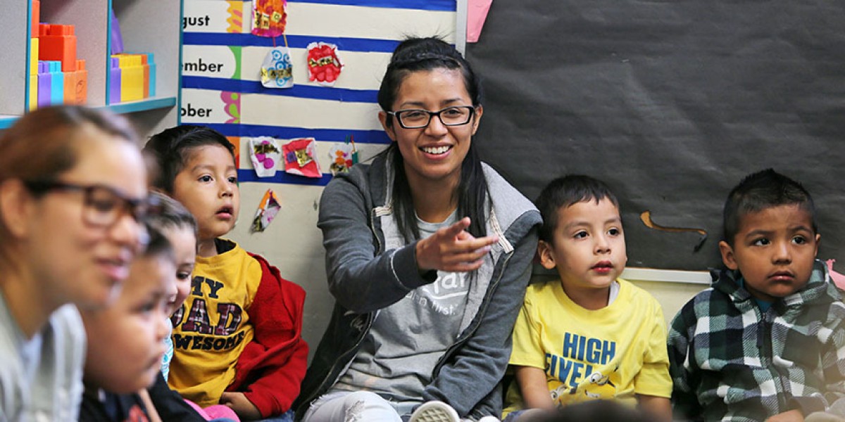 A student sitting on a floor surrounded by children.