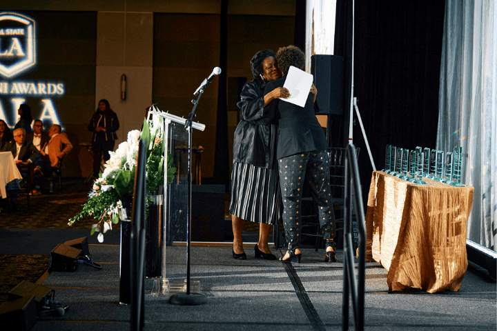 President Berenecea Johnson Eanes hugging an alum onstage at the 2024 Alumni Awards Gala