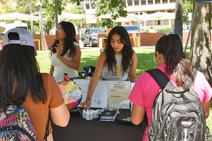 Staff speaking with students gathered at a tabling events.