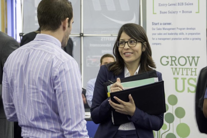 Student in professional clothes talks to an employer at the career fair