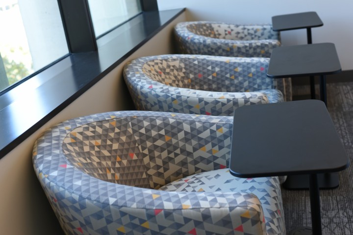 Row of upholstered chairs with small tables.