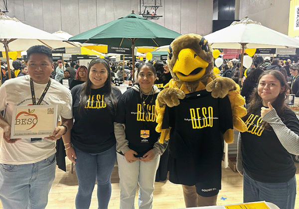 Students wearing BESO shirts standing with Eddie the GOlden Eagle