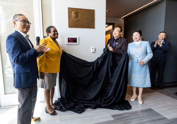 A group of people unveiling a bronze plaque on a wall.