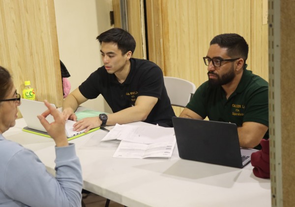 Two students help a community member with their tax return.