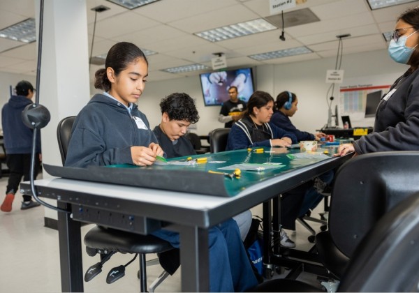 Students participate in a hands-on STEM workshop at Cal State LA, working on electronics projects at a lab table during MESA STEM Day. 
