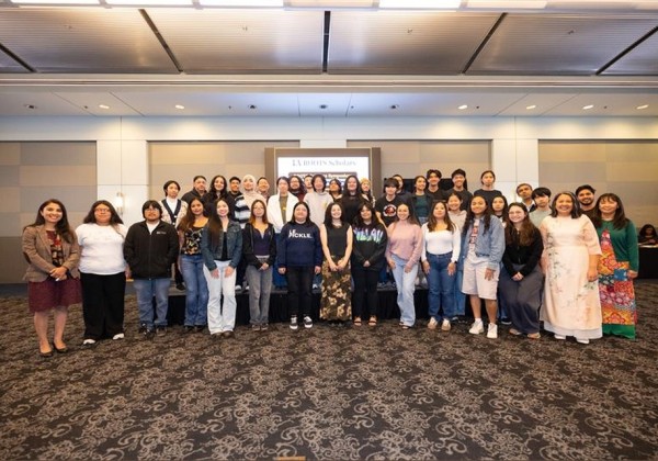 Group photo of Cal State LA Roots Scholars standing together in a conference room, smiling at the camera during a recognition event.