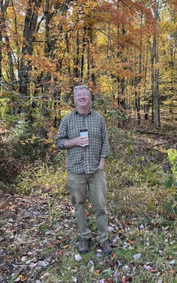 Photo of Chris Endy in the wood with a cup of coffee