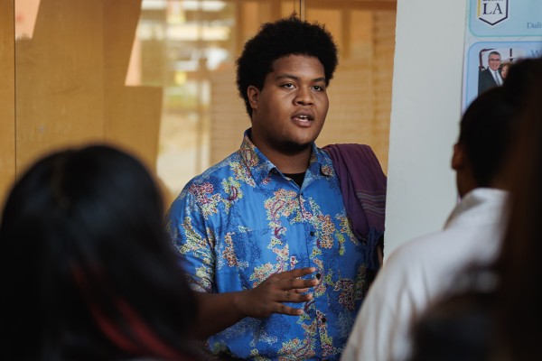 Student presenting his poster board to a large group of people