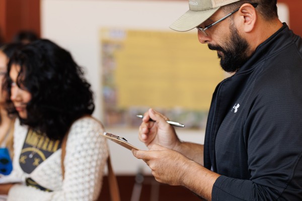 Student taking notes while listening to a poster presentation