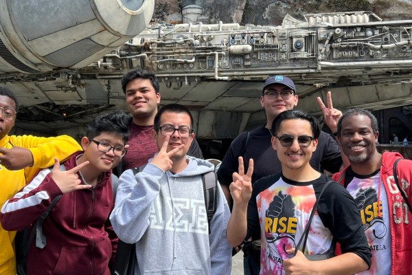 Seven men smiling in front of a mechanic ship.