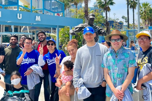 Group of men and women standing and smiling in front of a blue structure