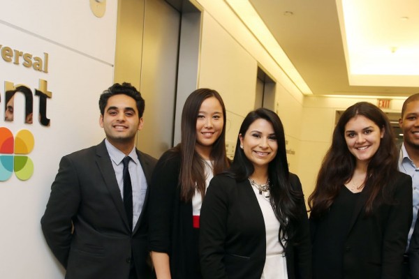 Group of Cal State LA students in business attire standing grouped in front of the NBC Universal Talent Lab sign. 