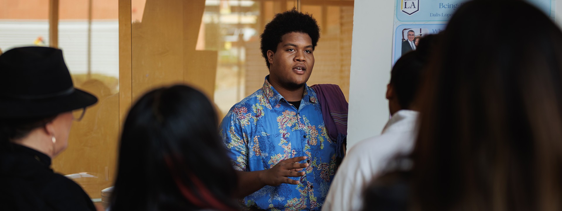 Student presenting his poster board to a large group of people