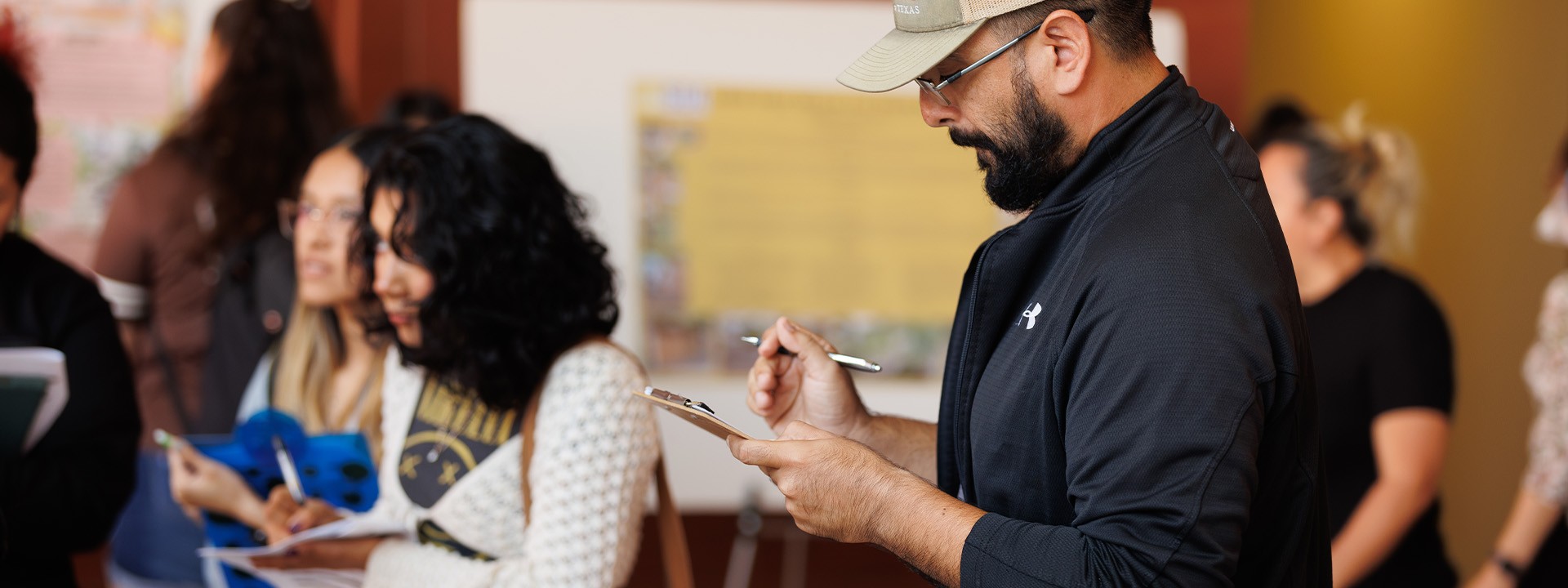 Student taking notes while listening to a poster presentation