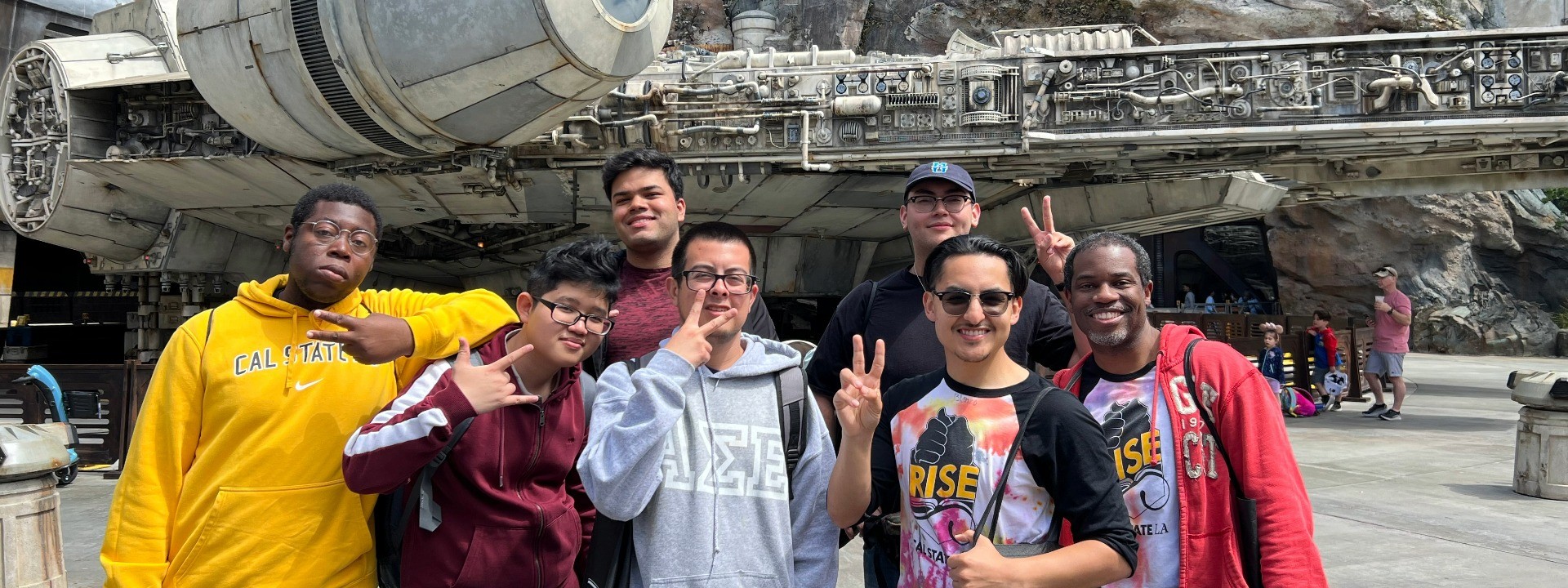 Seven men smiling in front of a mechanic ship.